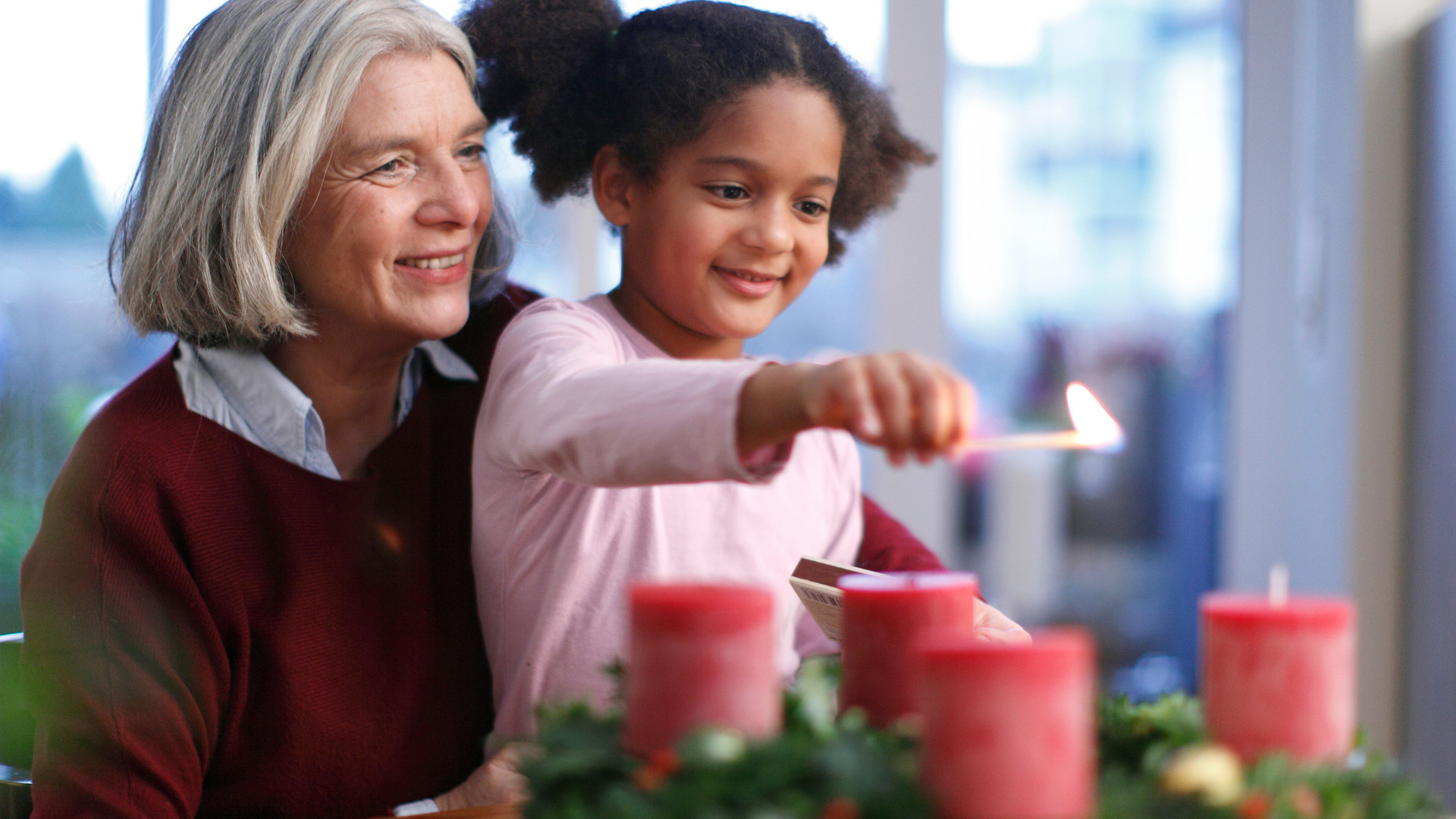Eldre dame har et barnebarn på fanget og tenner adventslys