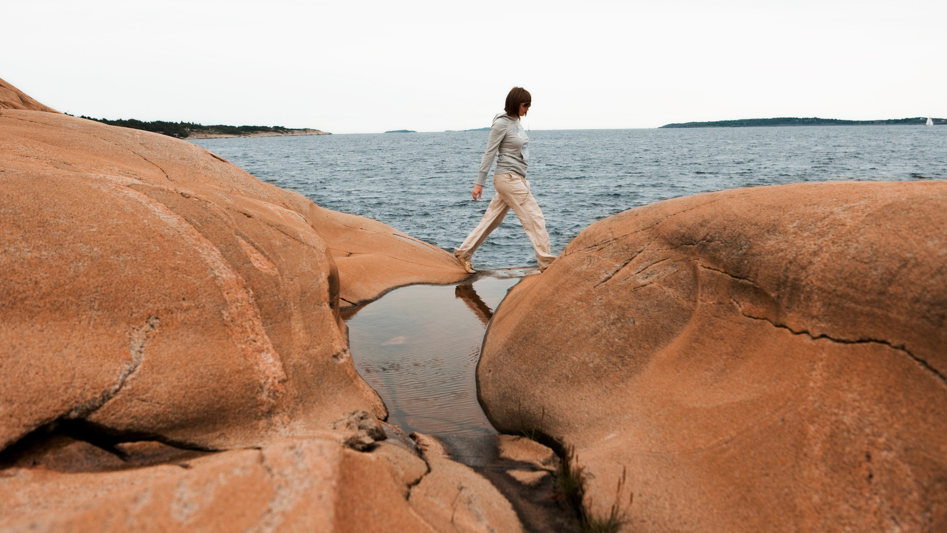 Kvinne hopper mellom svabergene i Engelsviken, Østfold en sommerdag