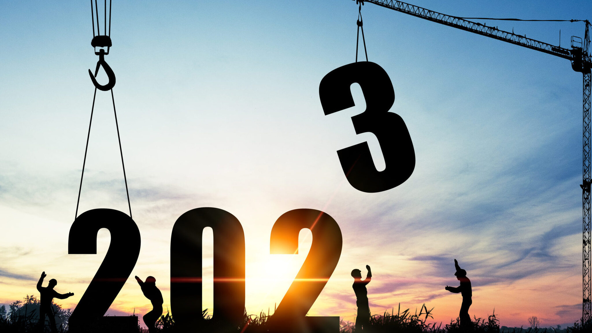 Siluett av arbeidere me kran som heiser ned tre tallet i 2023