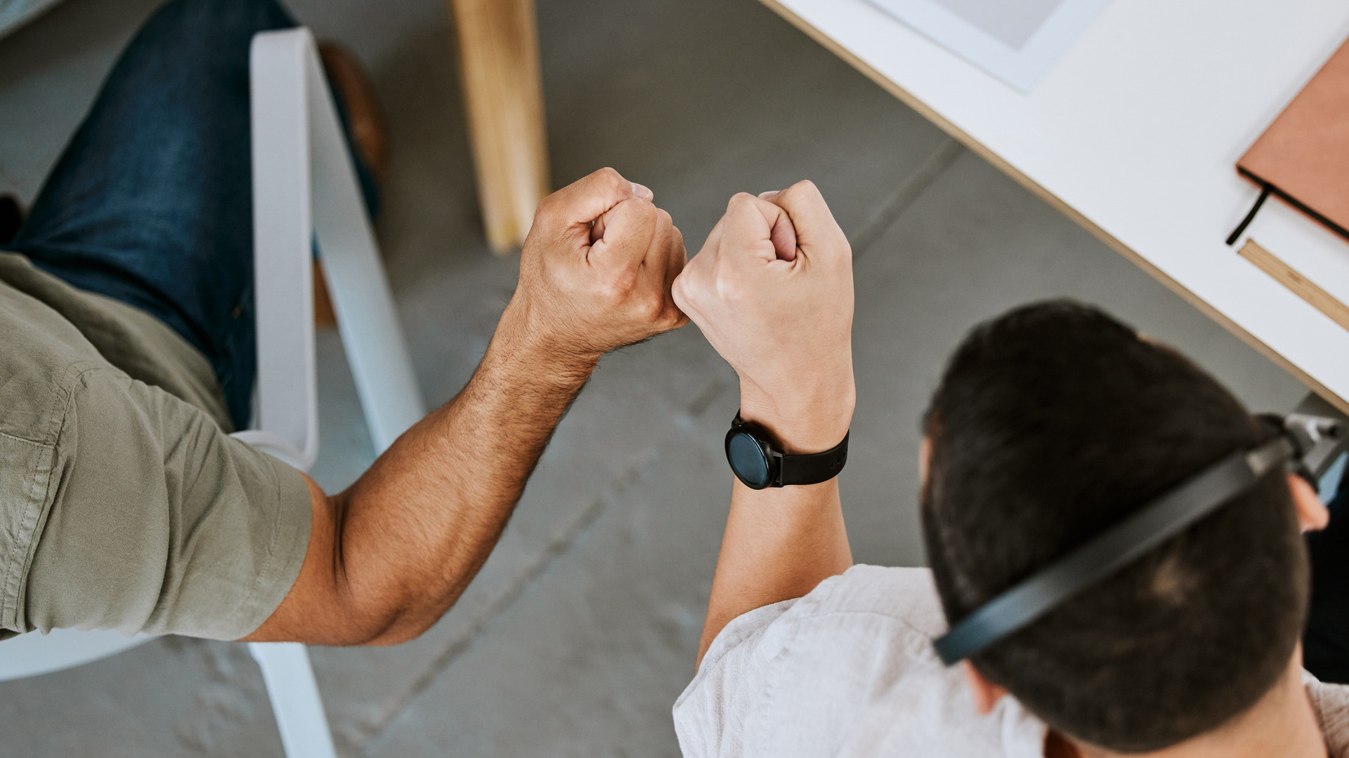 Vi ser to mannlige kollegaer overfra hvor de skår nevene mot hverandre